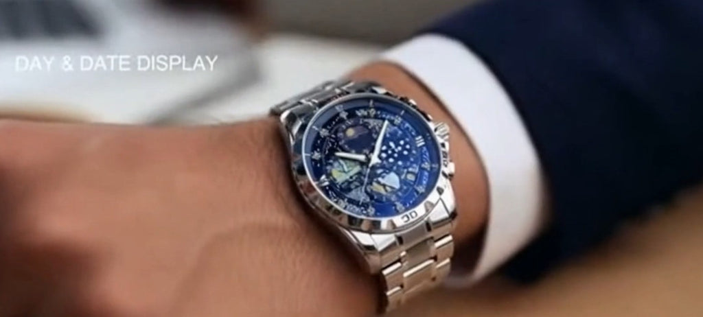 Close-up of a wrist wearing a silver watch with a blue face, on a blurred background.