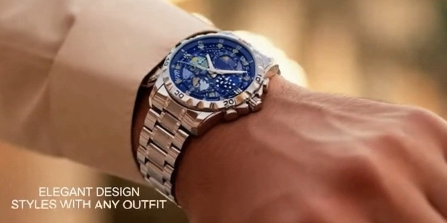 Close-up of a wrist wearing a silver watch with a blue face, on a blurred background.